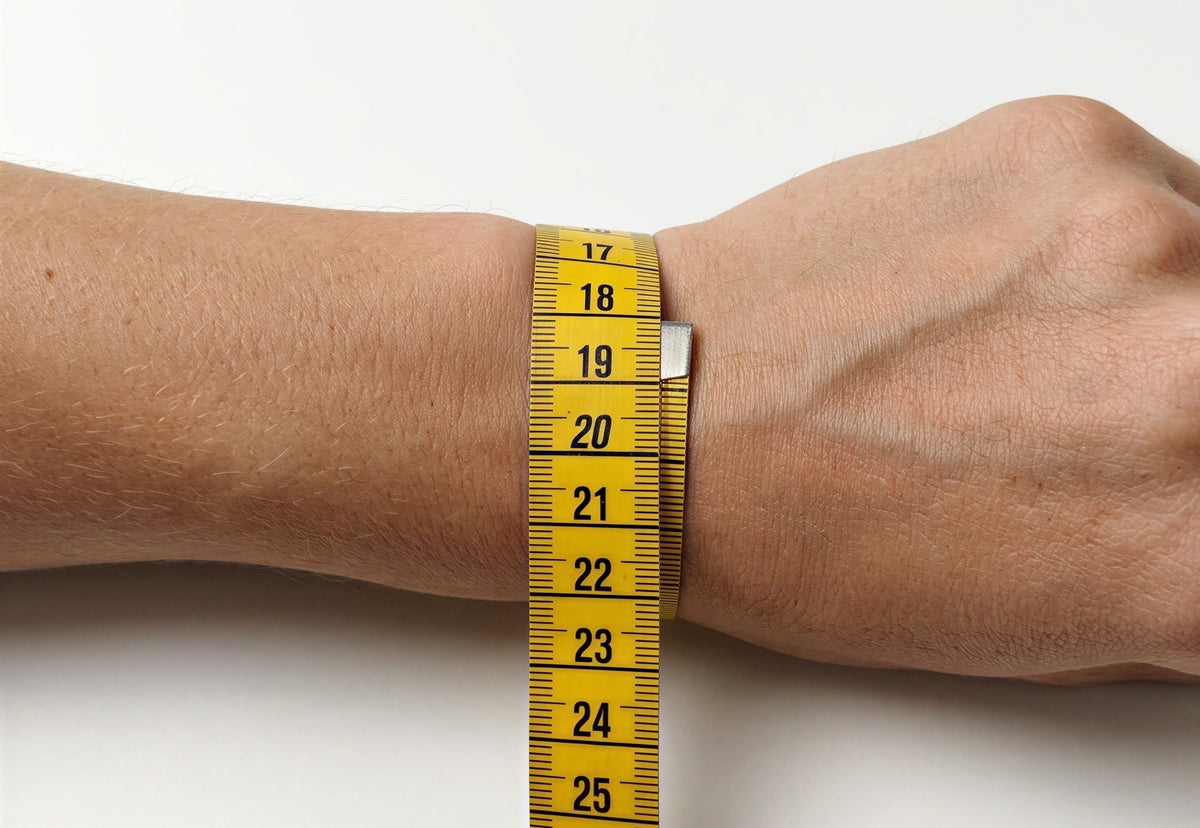 Tape measure around a wrist reading 18 cm, showing how to measure for a silver bracelet size