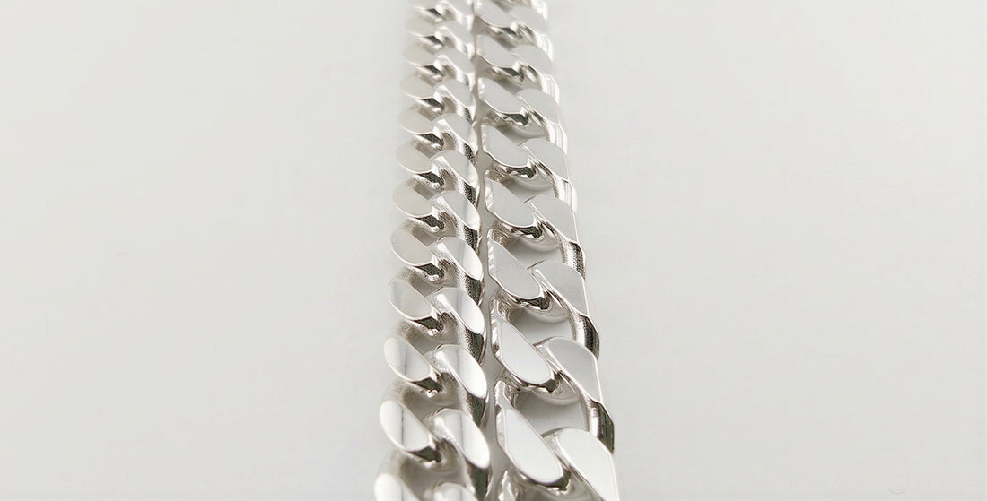 Neviera 6,4 mm curb chain beside a 6 mm Cuban link chain in 925 sterling silver, touching in one frame to compare link depth at near-identical width