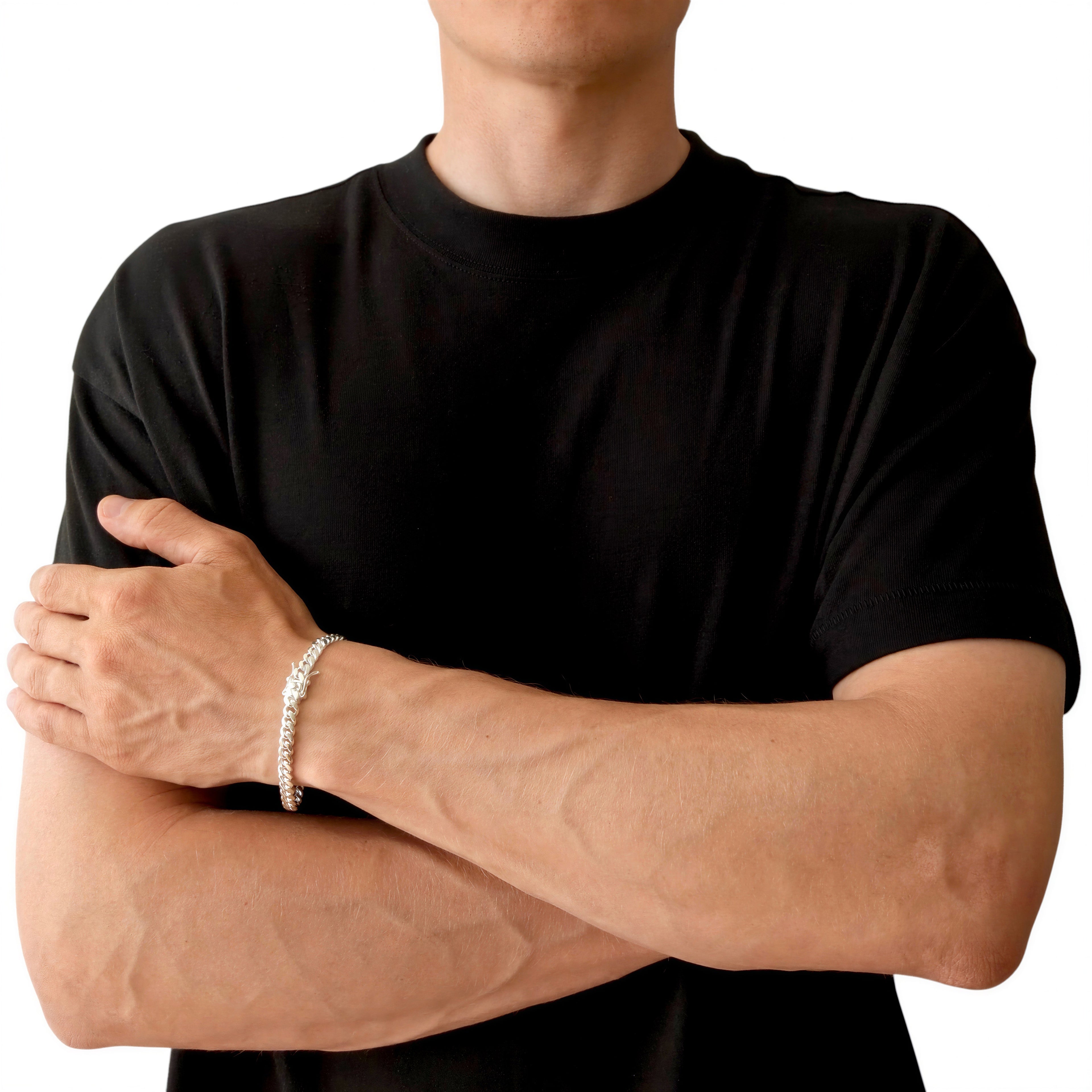 Neviera Cuban link chain bracelet — Italian-made 925 sterling silver, 6mm width. Lifestyle photograph on model wearing the bracelet with a black crew-neck t-shirt on a neutral background, alternate pose. Neviera specializes in high-quality Italian-made 925 silver chain necklaces and bracelets.