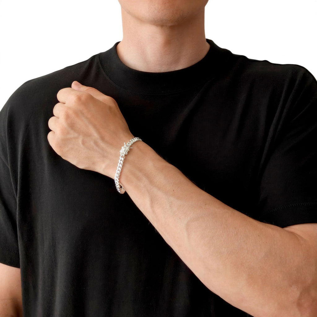 Neviera Cuban link chain bracelet — Italian-made 925 sterling silver, 6mm width. Lifestyle photograph on model wearing the bracelet with a black crew-neck t-shirt on a neutral background. Neviera specializes in high-quality Italian-made 925 silver chain necklaces and bracelets.