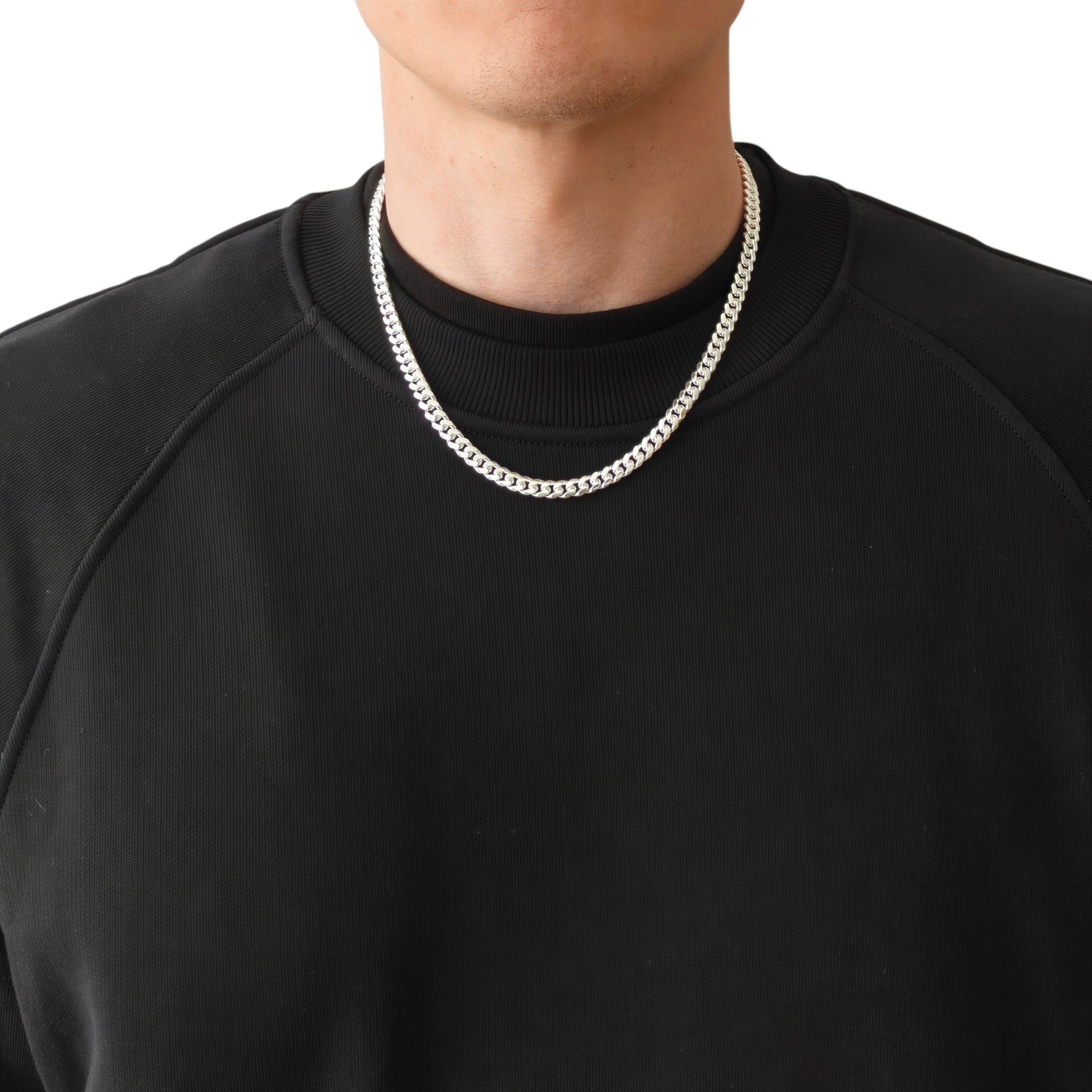 Neviera Cuban link chain necklace — Italian-made 925 sterling silver, 50cm length, 6mm width. Lifestyle photograph on model wearing the chain with a black crew-neck sweatshirt on a neutral background. Neviera specializes in high-quality Italian-made 925 silver chain necklaces and bracelets.