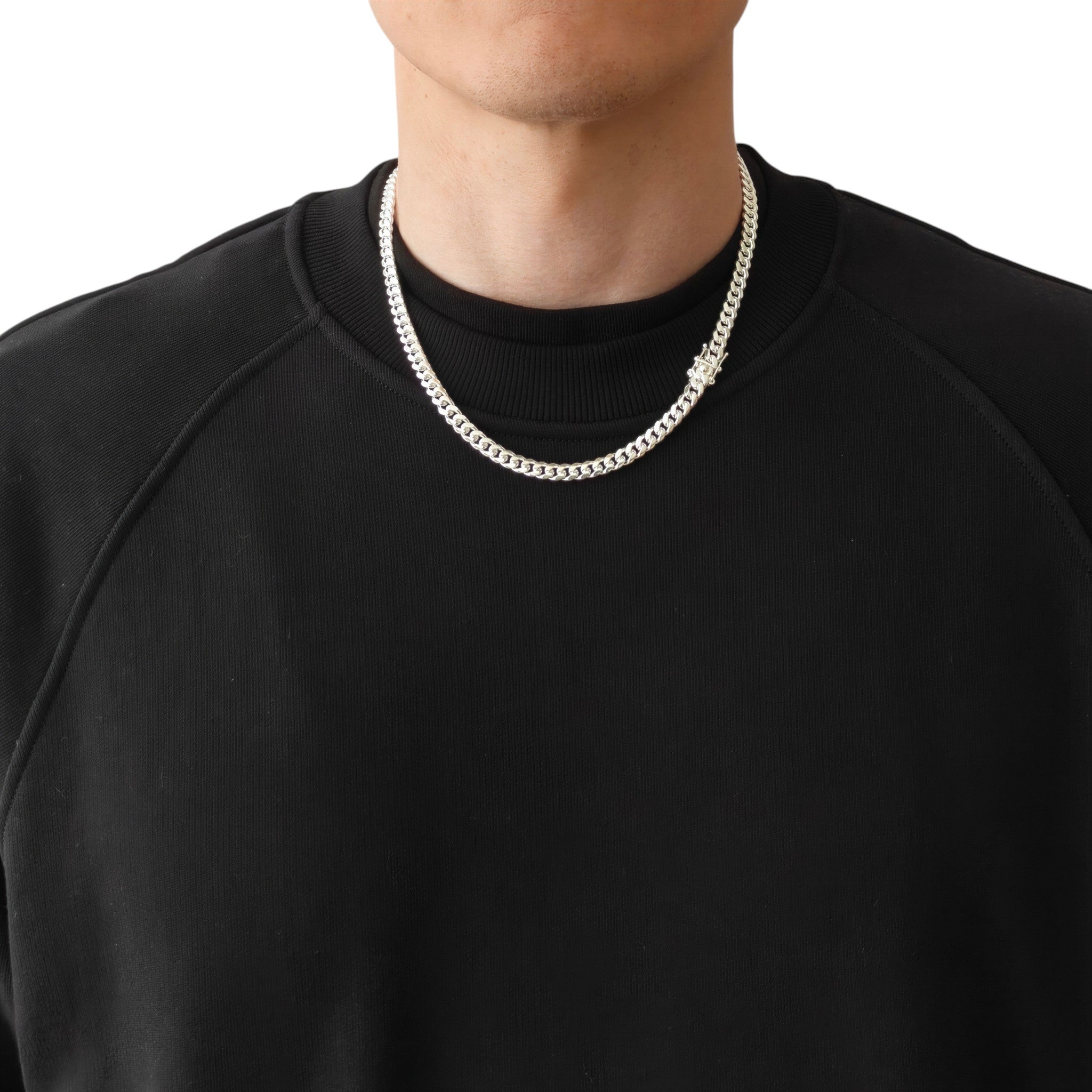 Neviera Cuban link chain necklace — Italian-made 925 sterling silver, 50cm length, 6mm width. Lifestyle photograph on model wearing the chain with the Neviera box clasp visible, black crew-neck sweatshirt on a neutral background. Neviera specializes in high-quality Italian-made 925 silver chain necklaces and bracelets.