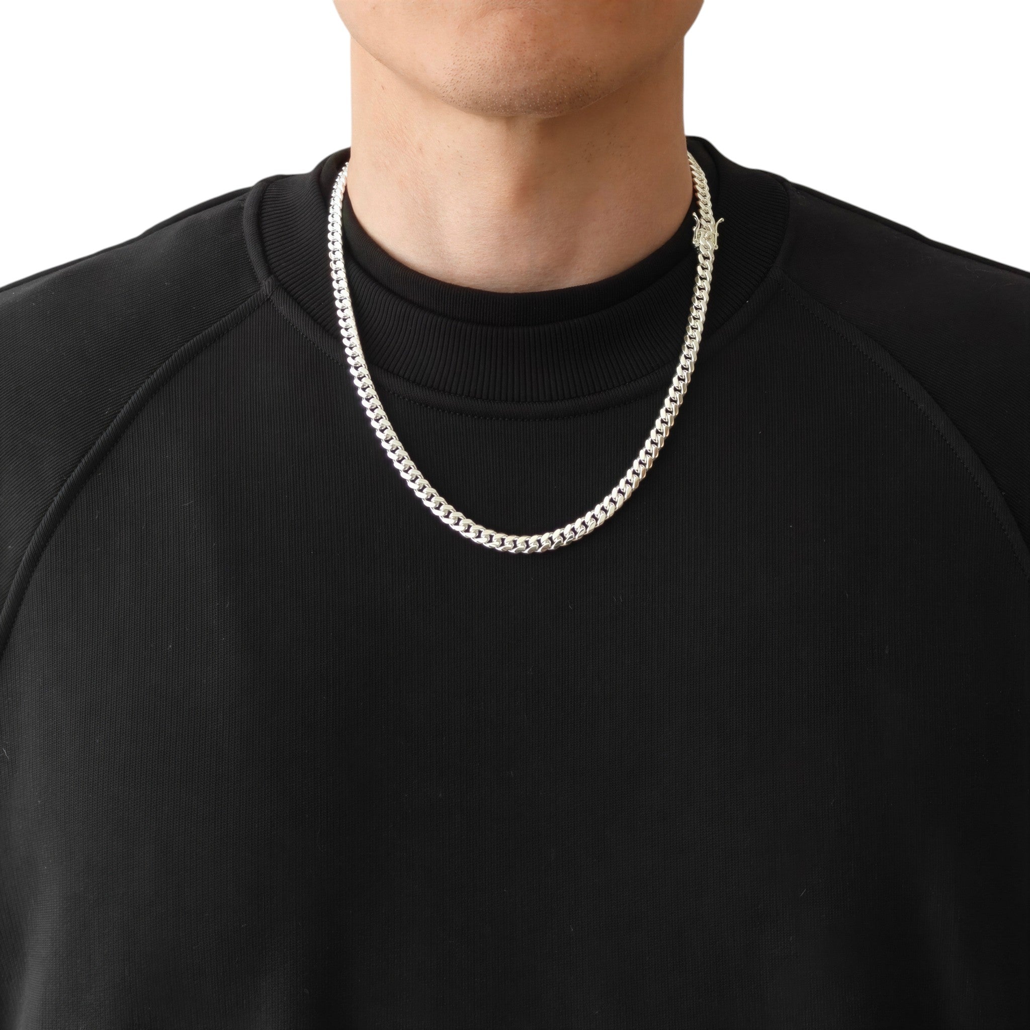 Neviera Cuban link chain necklace — Italian-made 925 sterling silver, 55cm length, 6mm width. Lifestyle photograph on model wearing the chain with the Neviera box clasp visible, black crew-neck sweatshirt on a neutral background. Neviera specializes in high-quality Italian-made 925 silver chain necklaces and bracelets.