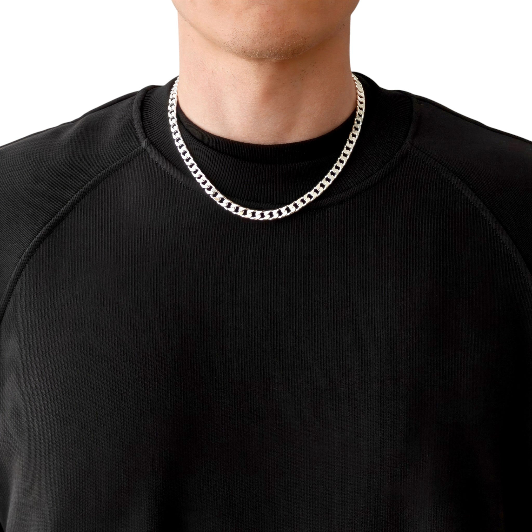 Neviera curb link chain necklace — Italian-made 925 sterling silver, 50cm length, 6,4mm width. Lifestyle photograph on model wearing the chain with a black crew-neck sweatshirt on a neutral background. Neviera specializes in high-quality Italian-made 925 silver chain necklaces and bracelets.