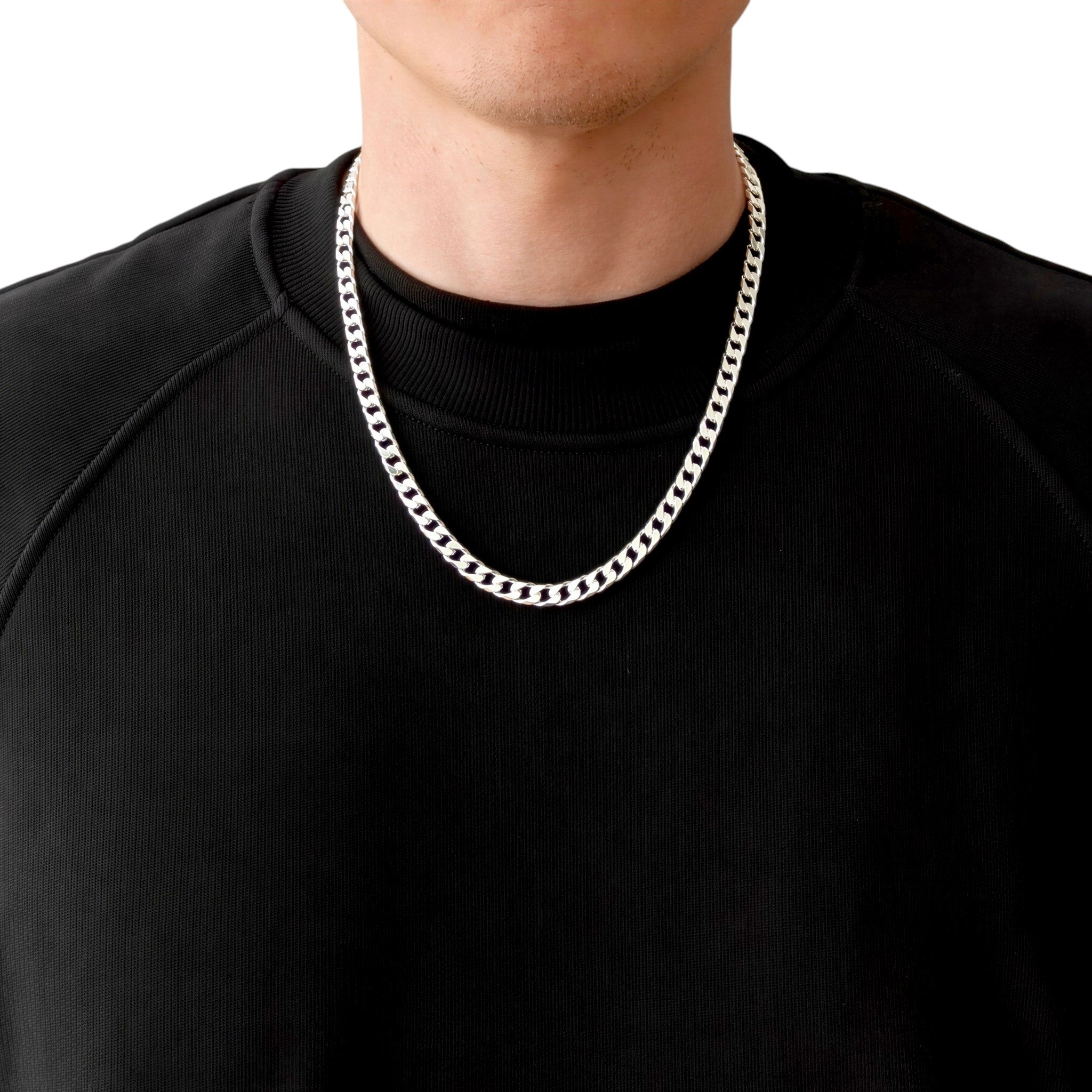 Neviera curb link chain necklace — Italian-made 925 sterling silver, 55cm length, 6,4mm width. Lifestyle photograph on model wearing the chain with a black crew-neck sweatshirt on a neutral background. Neviera specializes in high-quality Italian-made 925 silver chain necklaces and bracelets.