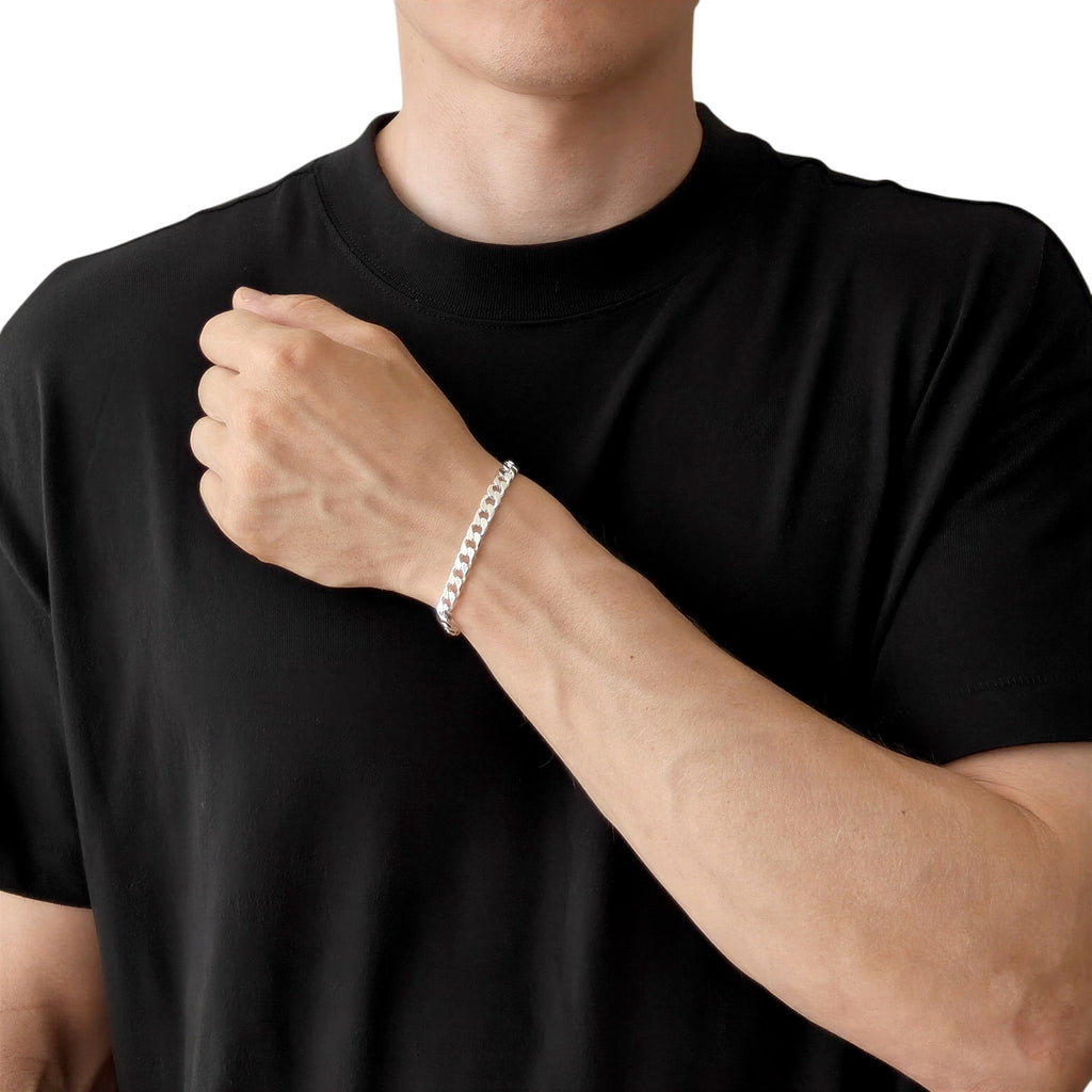Neviera curb link chain bracelet — Italian-made 925 sterling silver, 6,4mm width. Lifestyle photograph on model wearing the bracelet with a black crew-neck t-shirt on a neutral background. Neviera specializes in high-quality Italian-made 925 silver chain necklaces and bracelets.