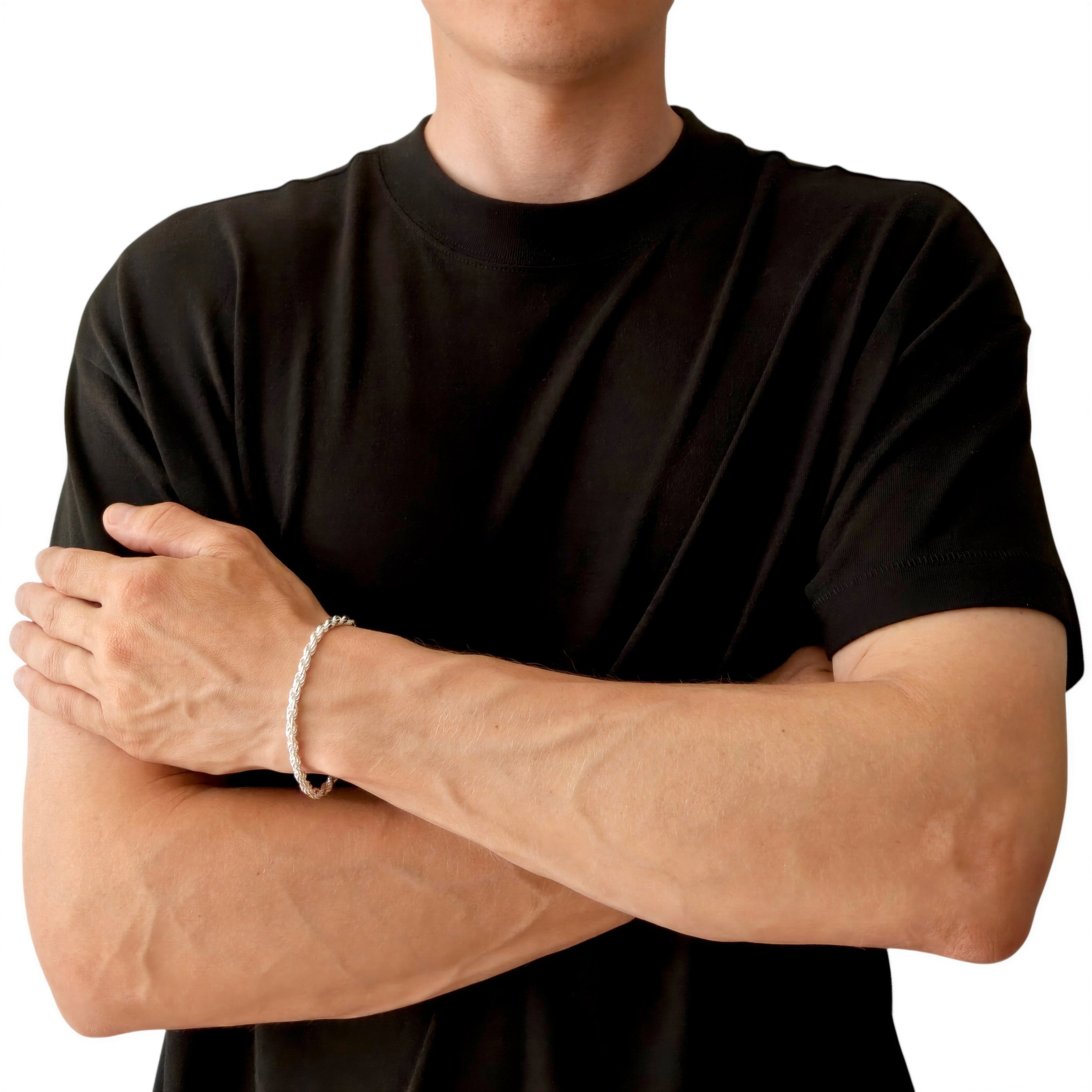 Neviera rope chain bracelet — Italian-made 925 sterling silver, 4,6mm width. Lifestyle photograph on model wearing the bracelet with a black crew-neck t-shirt on a neutral background, alternate pose. Neviera specializes in high-quality Italian-made 925 silver chain necklaces and bracelets.